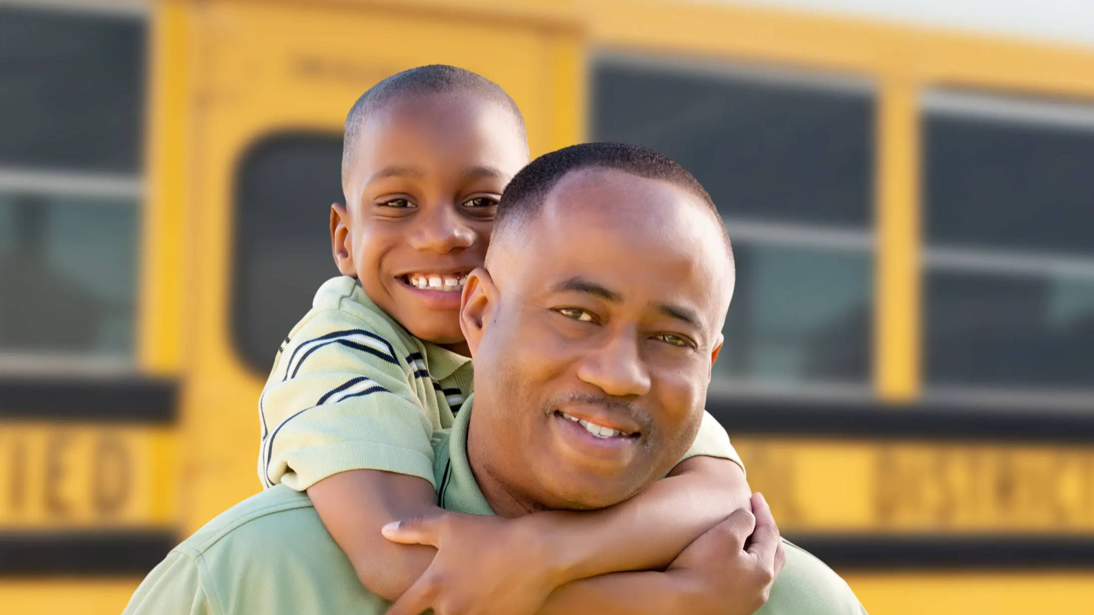 Dad and son hugging by school bus