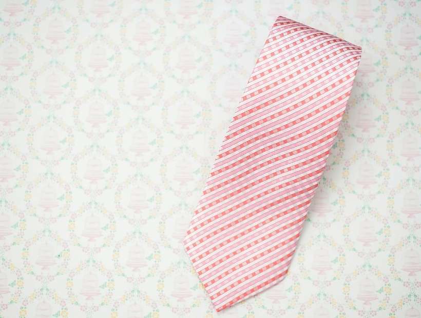 A pink gingham tie displayed on top of wedding wrapping paper