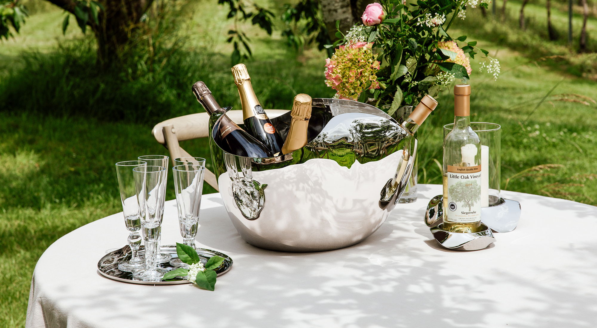 Drift Champagne Bucket with champagne bottles and glasses on a table outdoors.