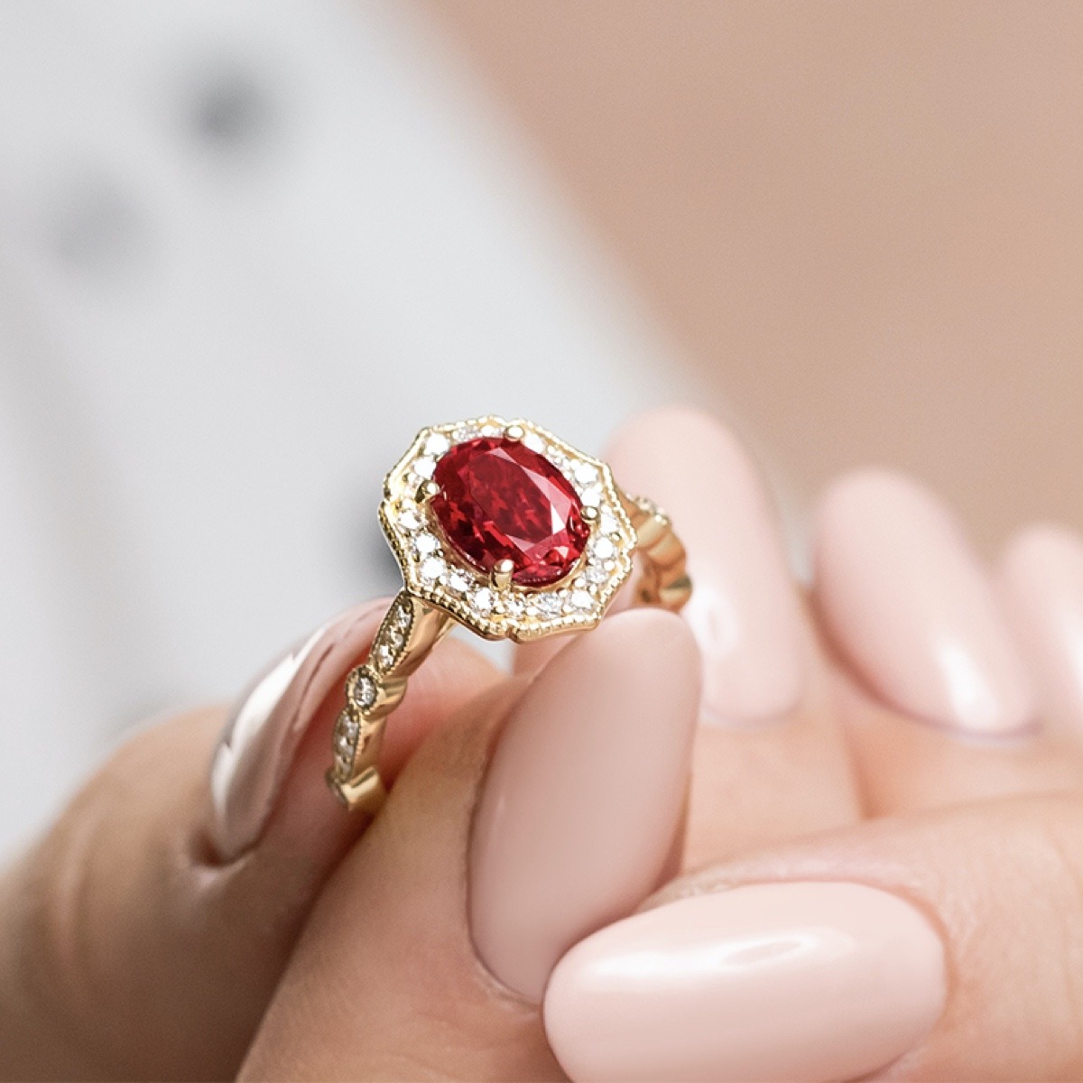 Antique style engagement ring with detailed filigree and a diamond halo surrounding a 2ct oval ruby in yellow gold