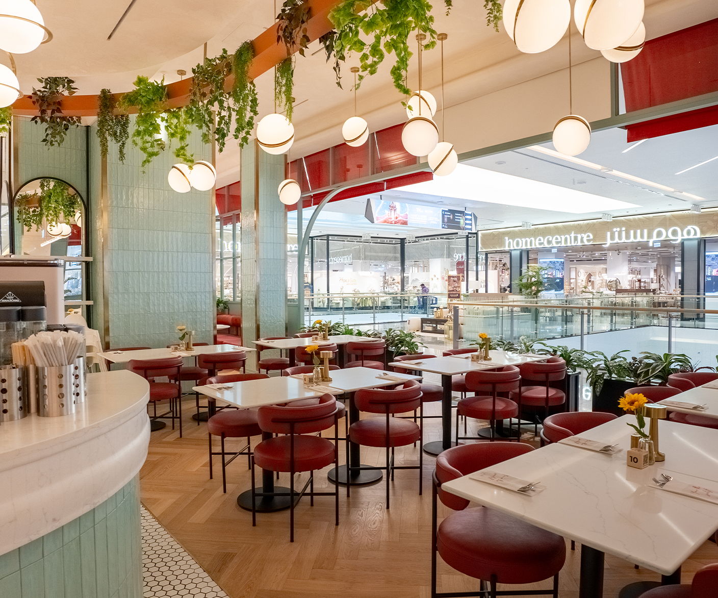 Interior of a modern restaurant with tables, chairs, and decorative plants.