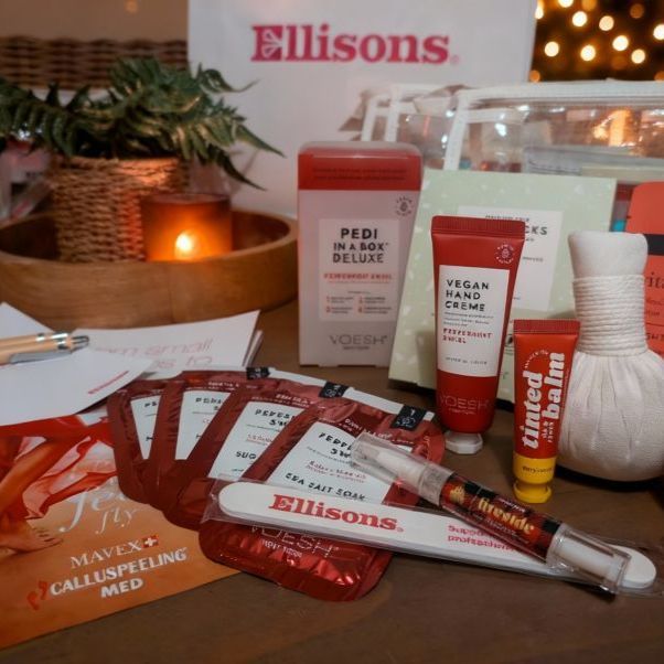 Cosmetic products from Ellisons displayed on a wooden table with decorative elements.