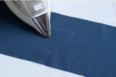 image of an iron erasing the white fabric marking pen marks on a blue piece of fabric