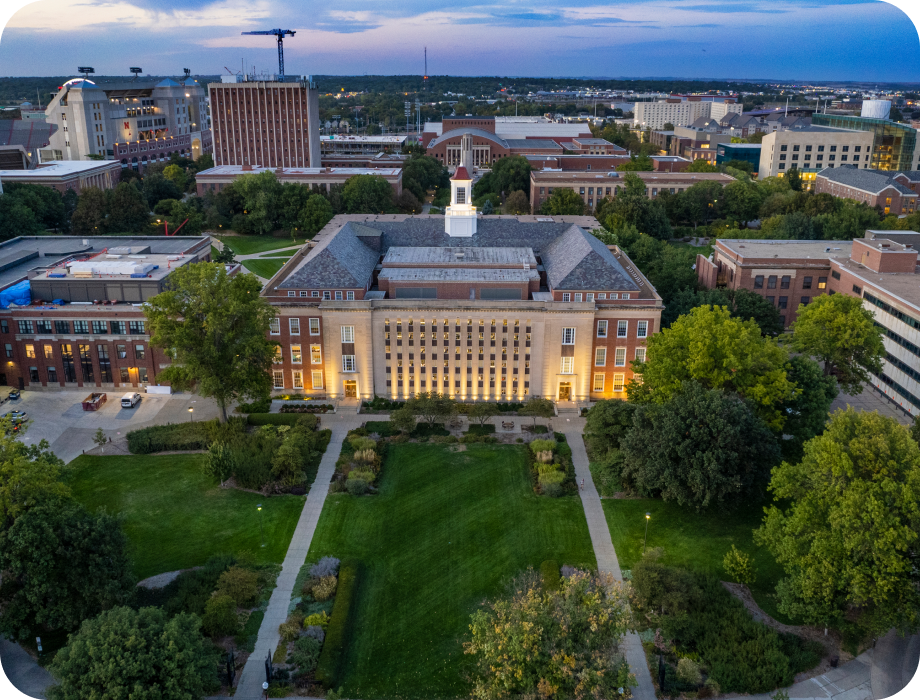 Aerial view of a university building with surrounding greenery at sunset.