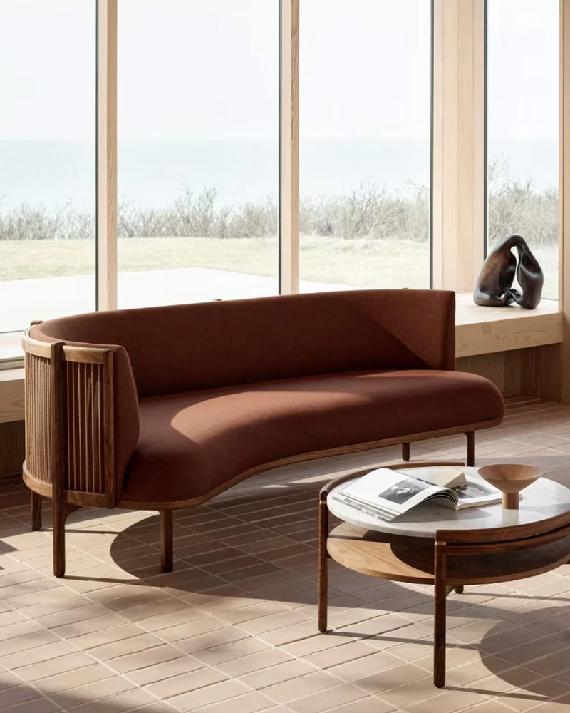 A modern Sideways sofa by Carl Hansen next to a round coffee table in a bright room.