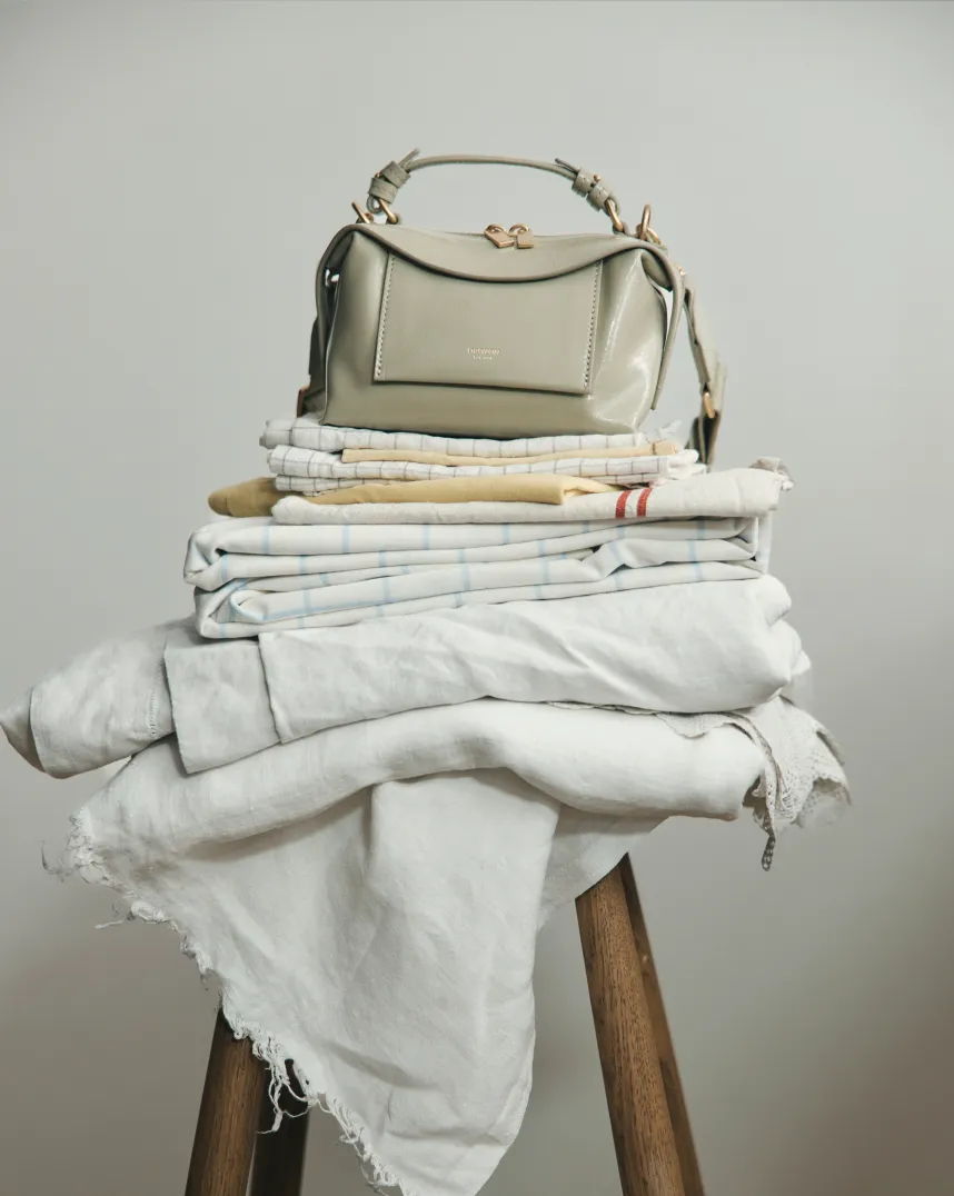 A stylish handbag placed on a stack of folded textiles.