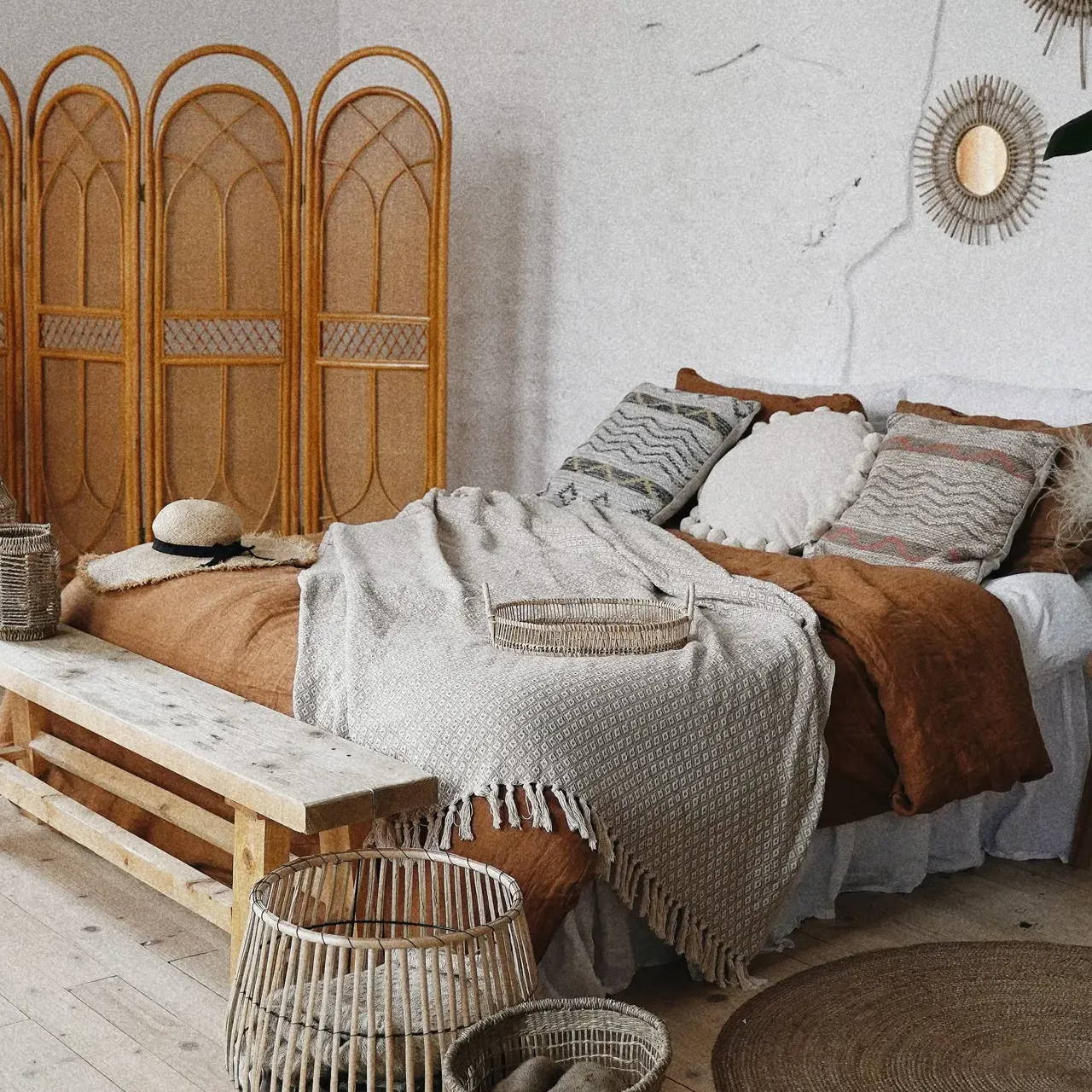 A cosy boho bedroom setting with burnt orange rust bed sheets.