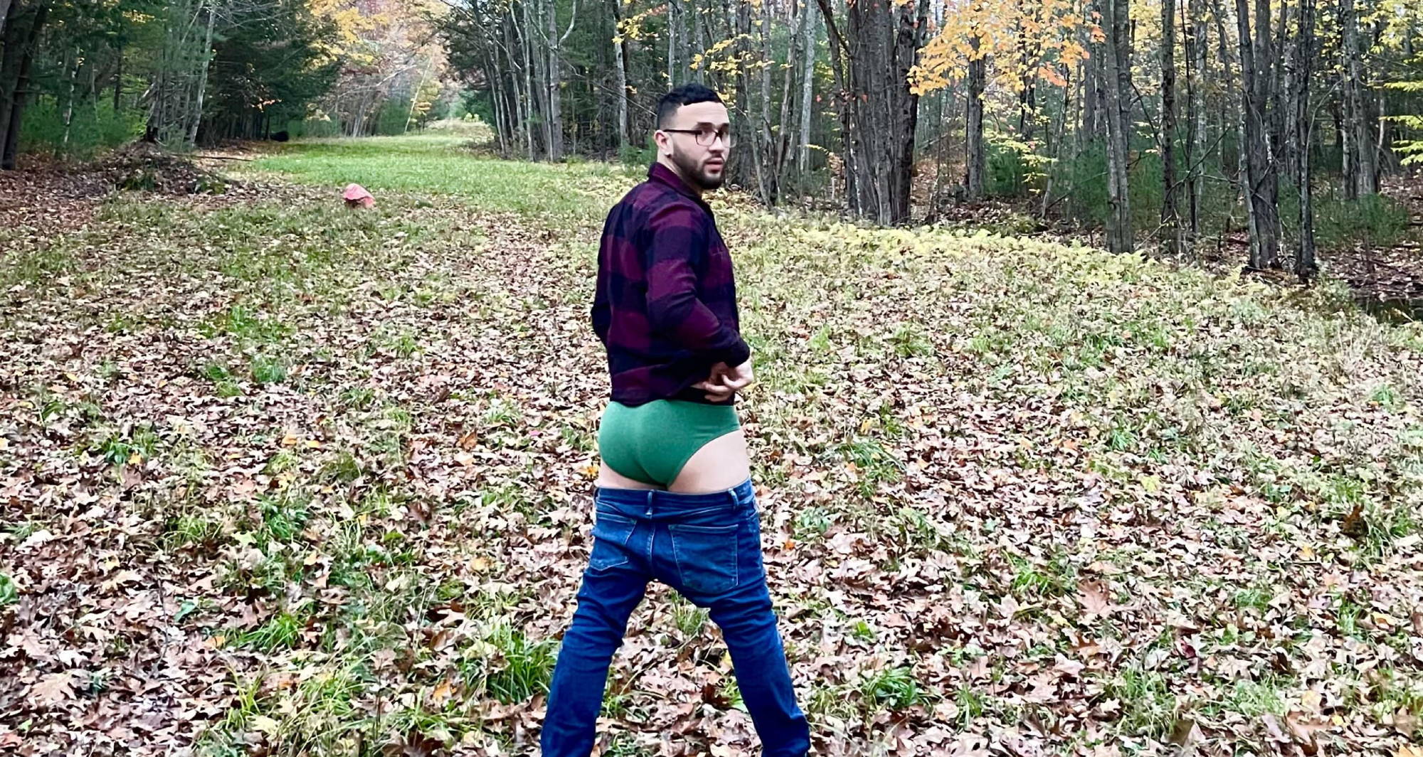 man from behind wearing a flannel and jeans pulled down exposing his green briefs undies