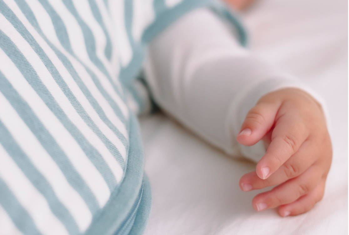 Baby's hand and arm with Woolbabe Sleeping in Tide