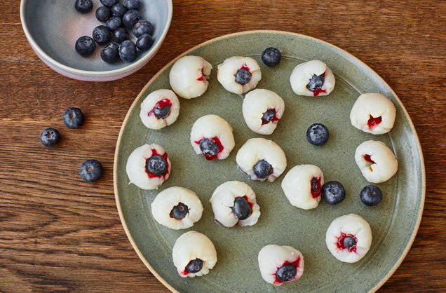 Plate of lychees filled with red jam and bluberry to make lychee eyeballs.