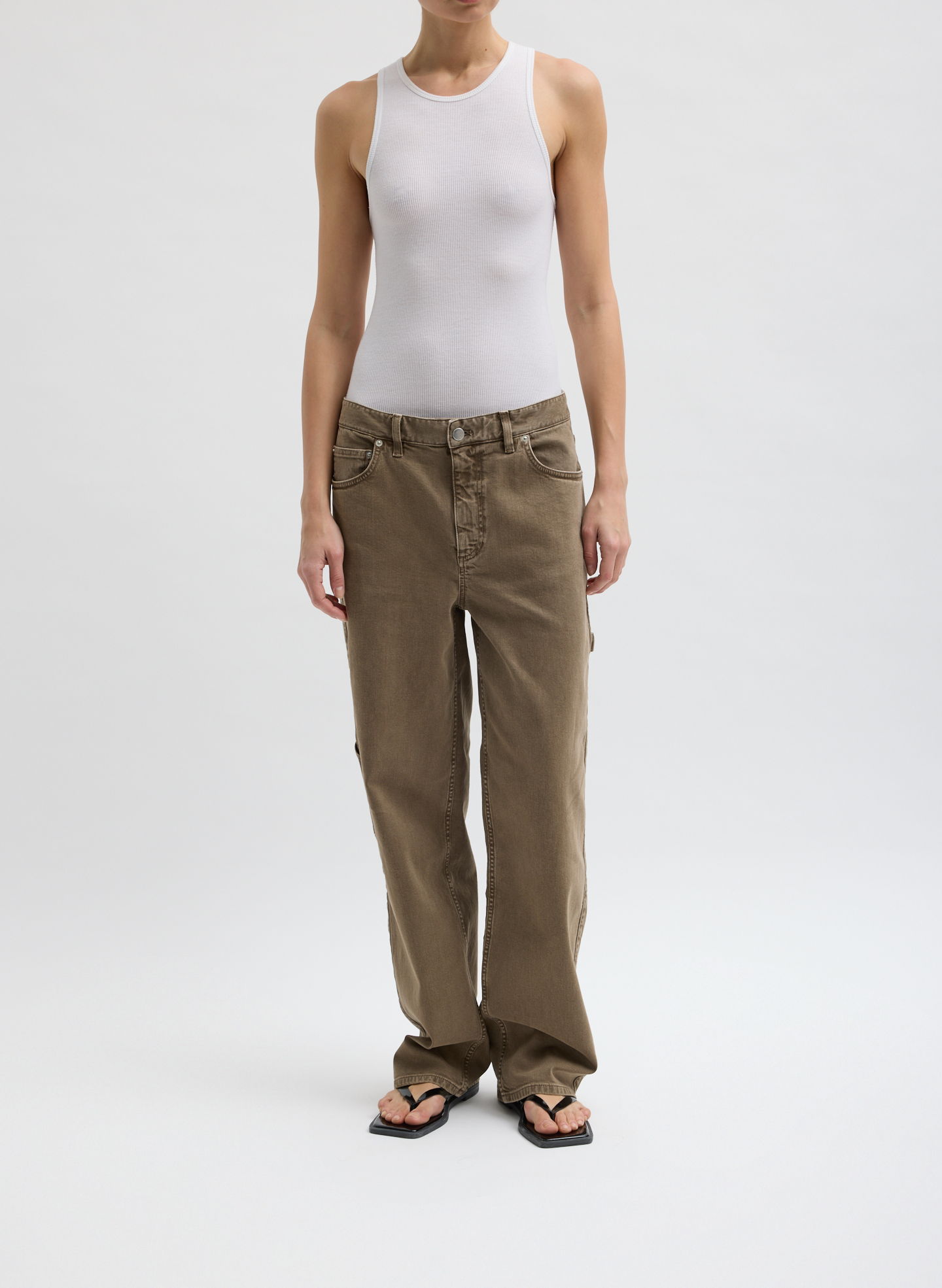 Person wearing a white tank top, brown pants, and flip-flops.