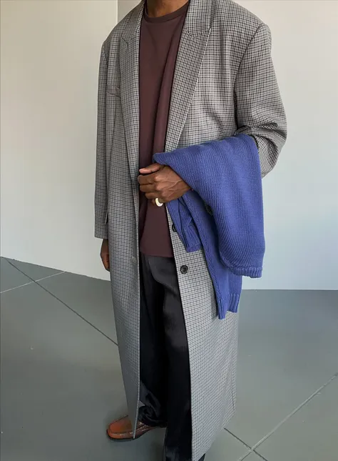 Person wearing a long coat and holding a blue blanket.