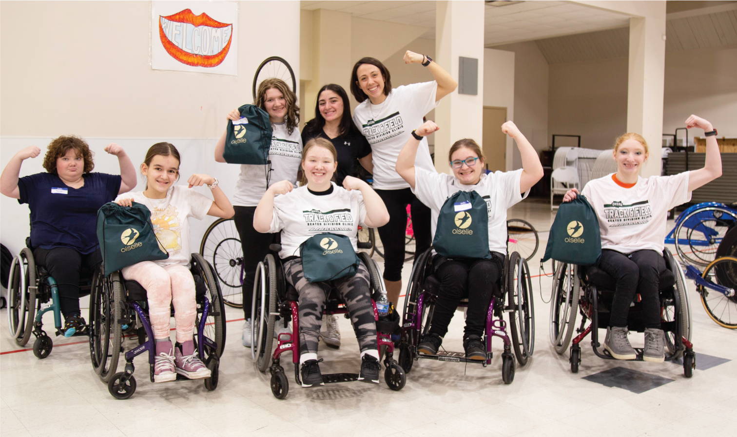 Young adaptive athletes pose in their wheelchairs with their gift bags from Oiselle