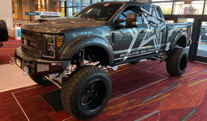Eric's lifted gray 2018 Ford F250 Super Duty with Rolling Big Power graphics on display at an indoor automotive show