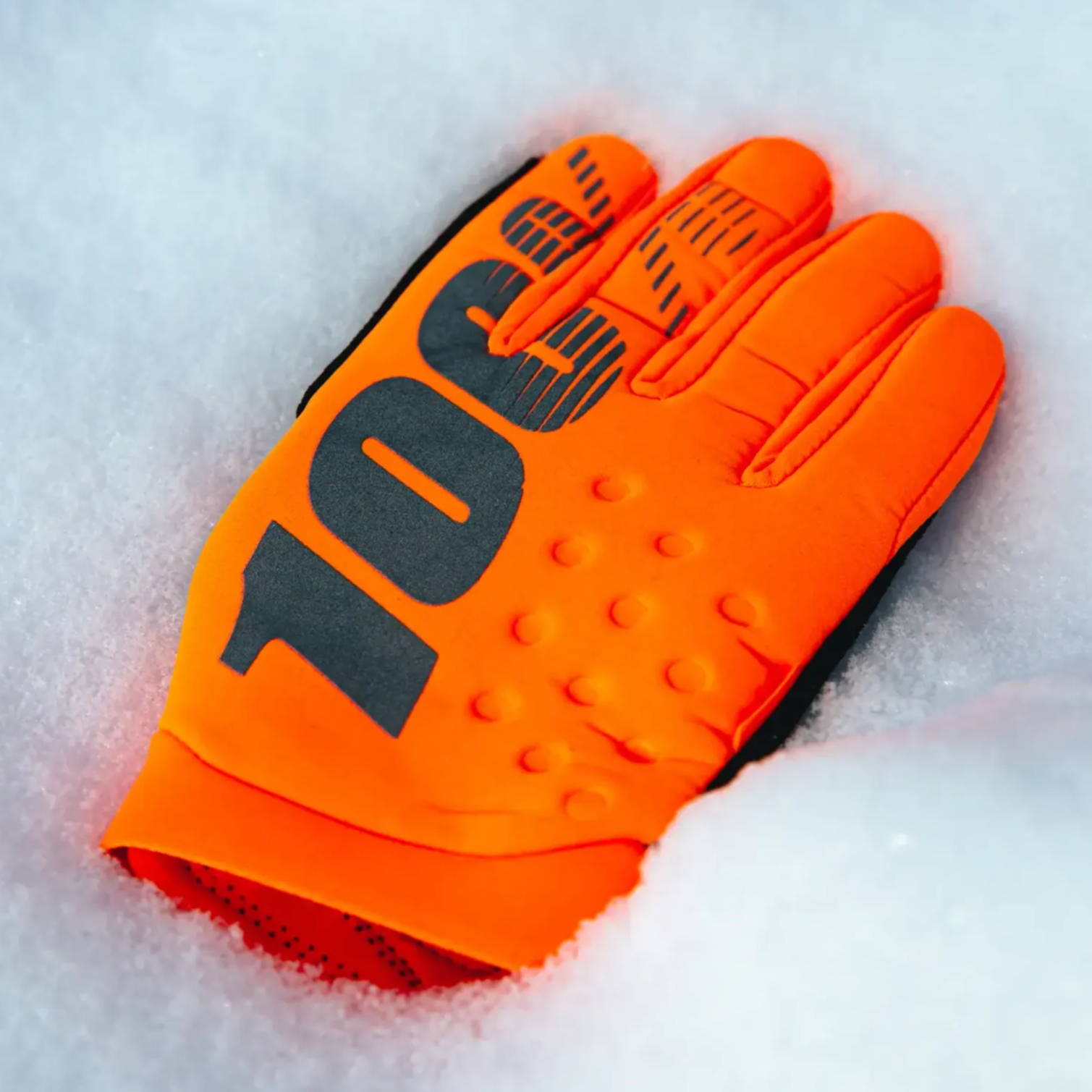 orange 100% brisker cold weather mtb gloves laying on snow