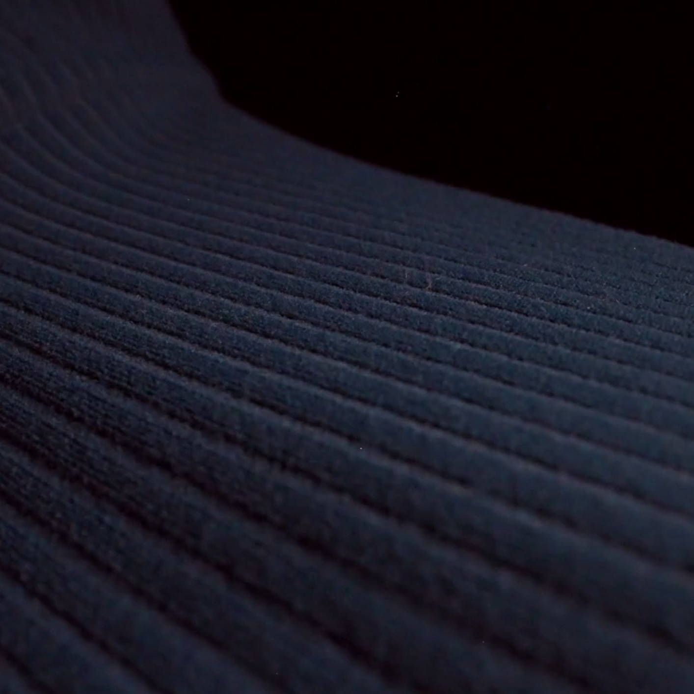Close-up of textured fabric with dark, wavy lines against a black background.