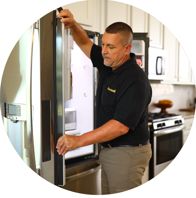 A Bodewell technician inspecting a refrigerator in a kitchen.