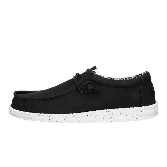 Black casual shoe with white sole and decorative laces.