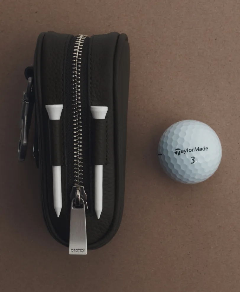 Black zippered case with two golf tees and a golf ball.