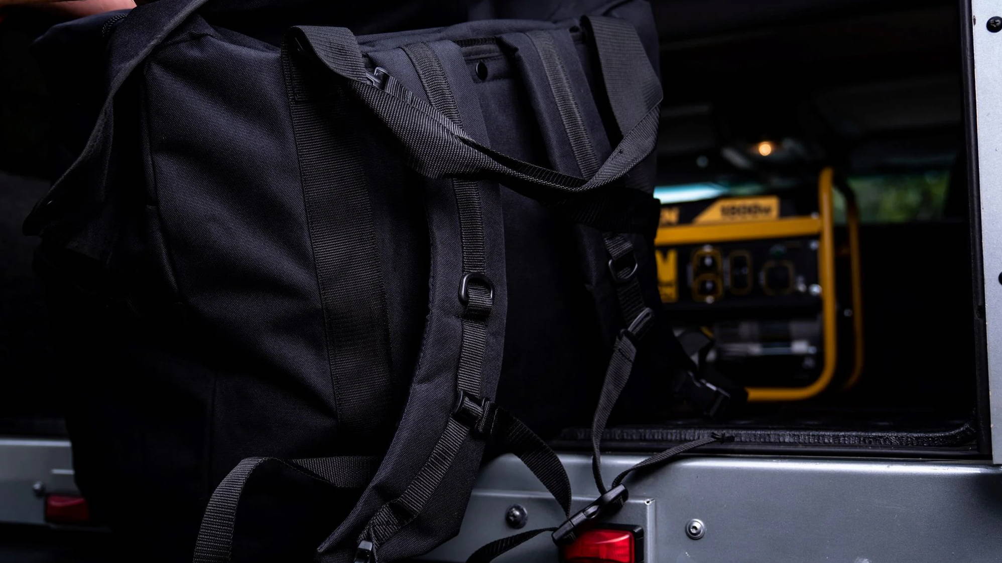 Black Jumbo Flyer's Kit Backpack with straps in the back of a SUV.