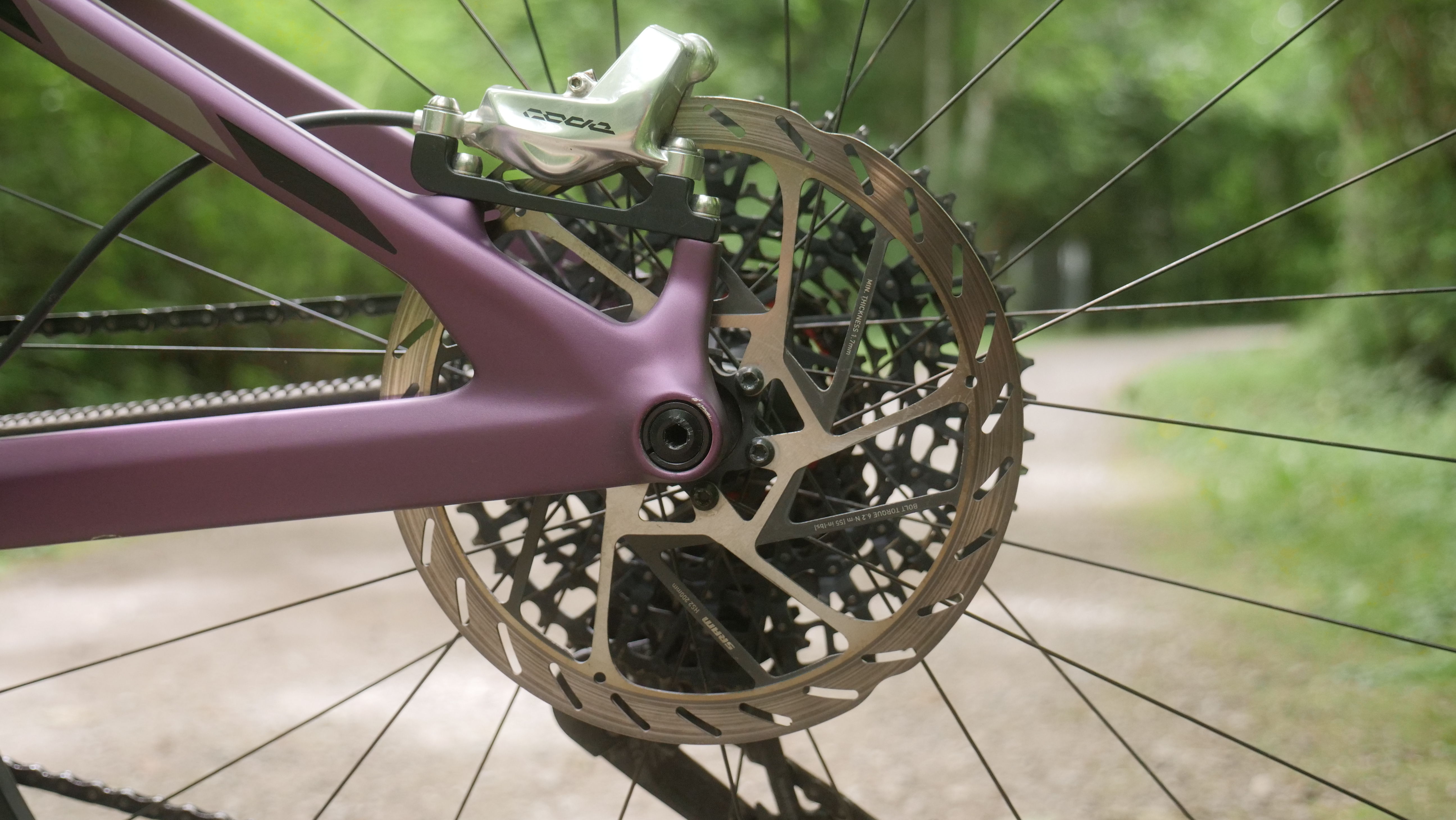 Close-up of a bicycle's rear wheel and brake disc on a path.