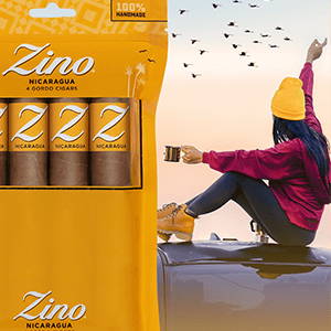 A freshpack of Zino Nicaragua Gordo cigars in front of a background of a girl having a hot drink while sitting on top of her car while watching the birds in the sky.