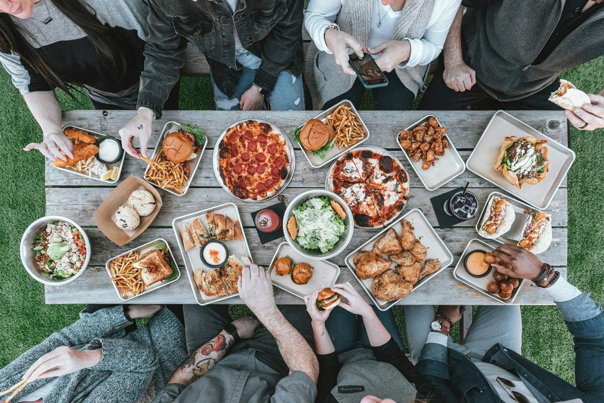 an overhead view of a farm to table meal with people sitting around eating