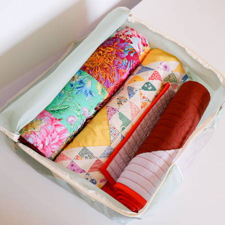 3 quilts rolled up in a quilt storage bag 