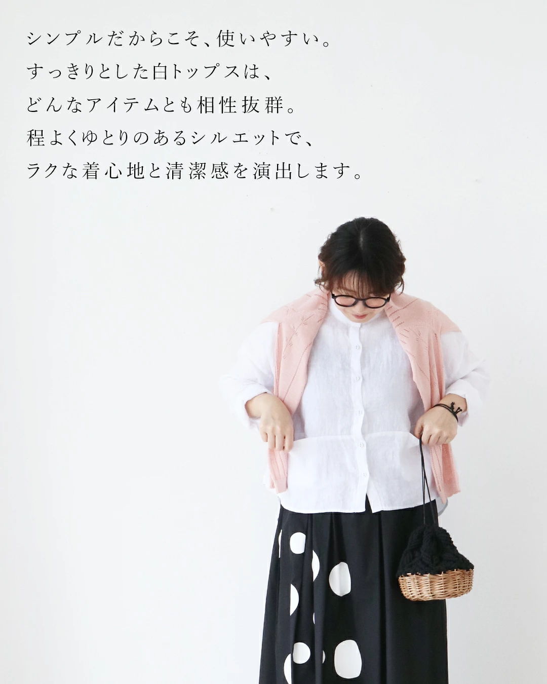 A person wearing a white top, pink cardigan, and polka dot skirt.