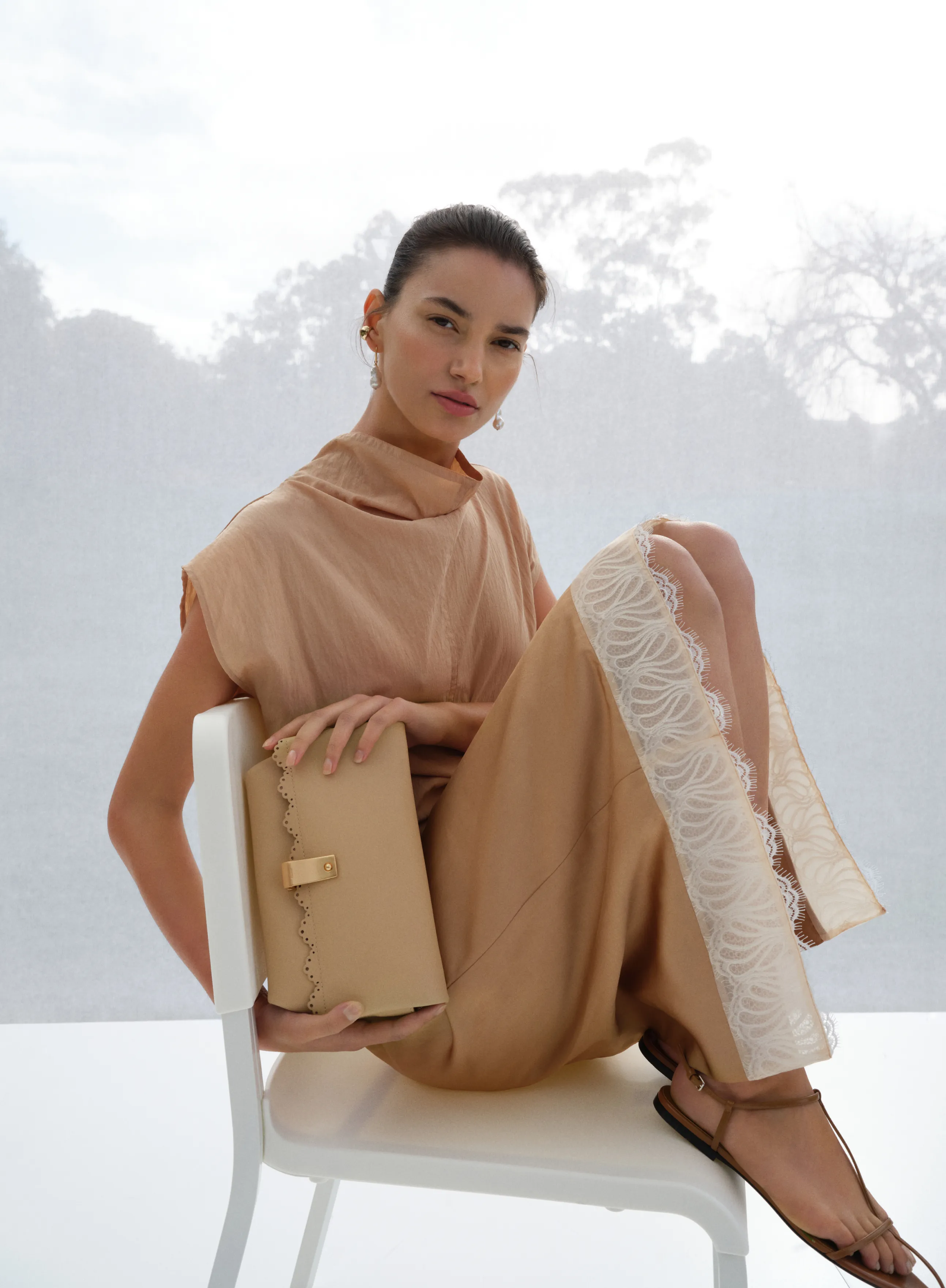 A woman in a stylish beige outfit sitting on a chair.