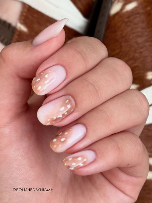 Classic Bambi nails featuring a soft nude base, warm fawn brown tips and delicate white deer-print spots on almond-shaped nails.