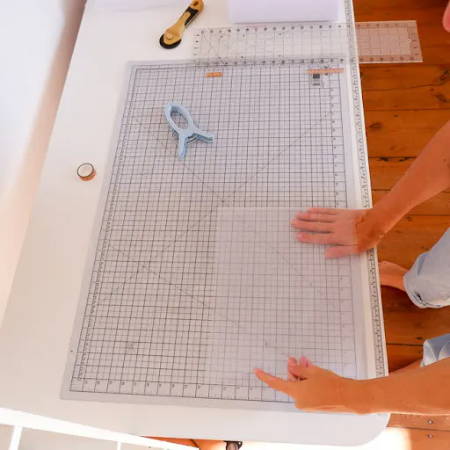 Fold the tulle fabric pieces before cutting into strips with a rotary cutter, quilting clamps on a big cutting mat