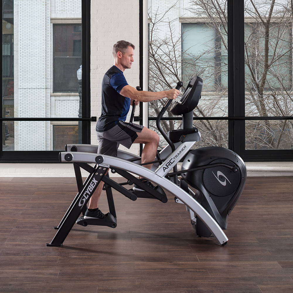 Man exercising on Cybex Total Body Arc Trainer in apartment home