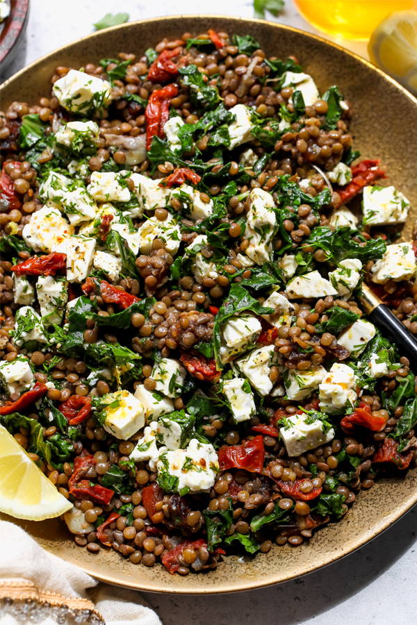 Cooked lentils with kale, sun-dried tomatoes with feta in a balsamic glaze