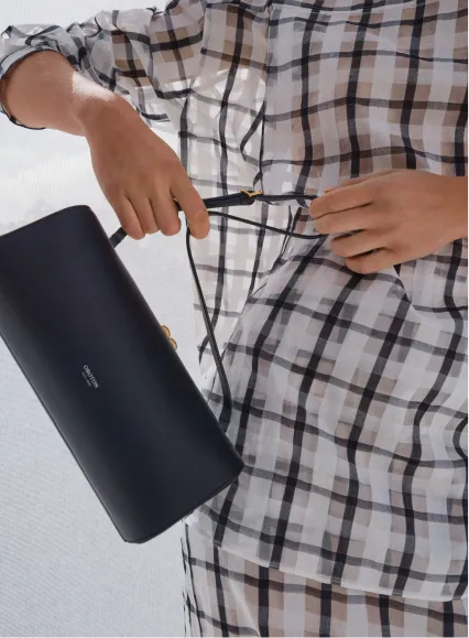 Person holding a black handbag while wearing a checkered shirt.