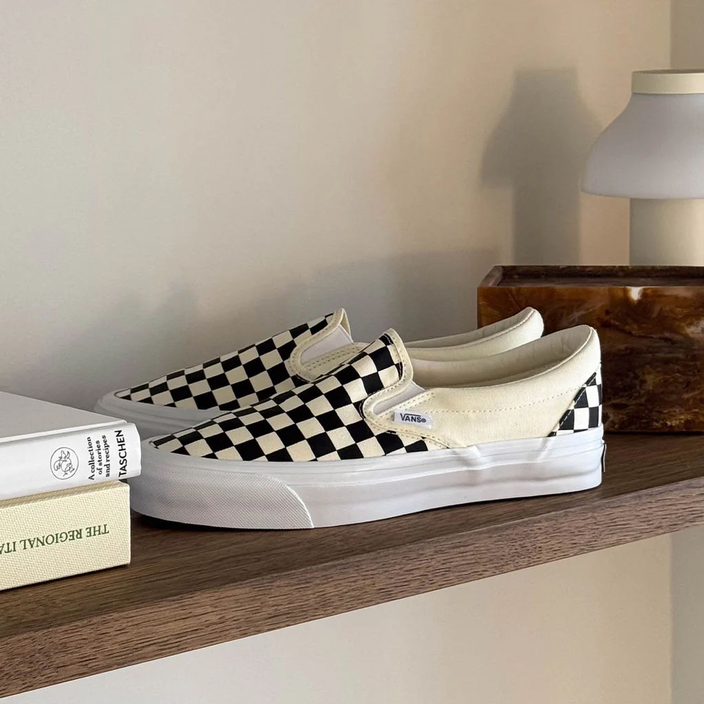 Black and white checkered slip-on shoes on a wooden shelf.