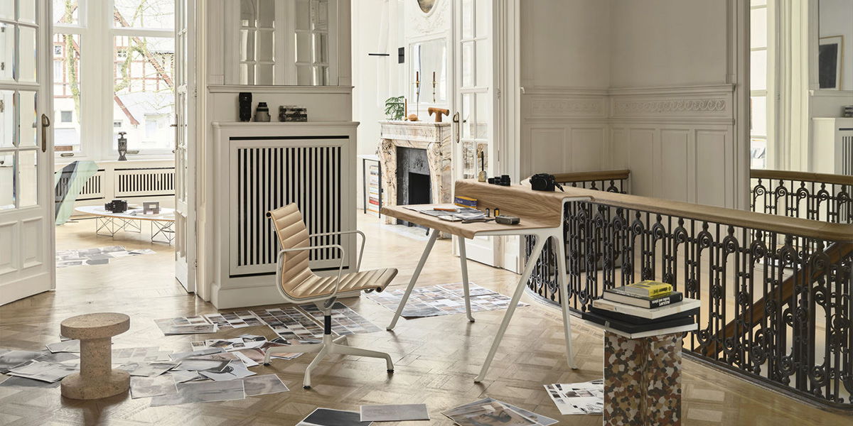 Modern workspace with wooden flooring, Vitra desk, chair, and decorative elements.