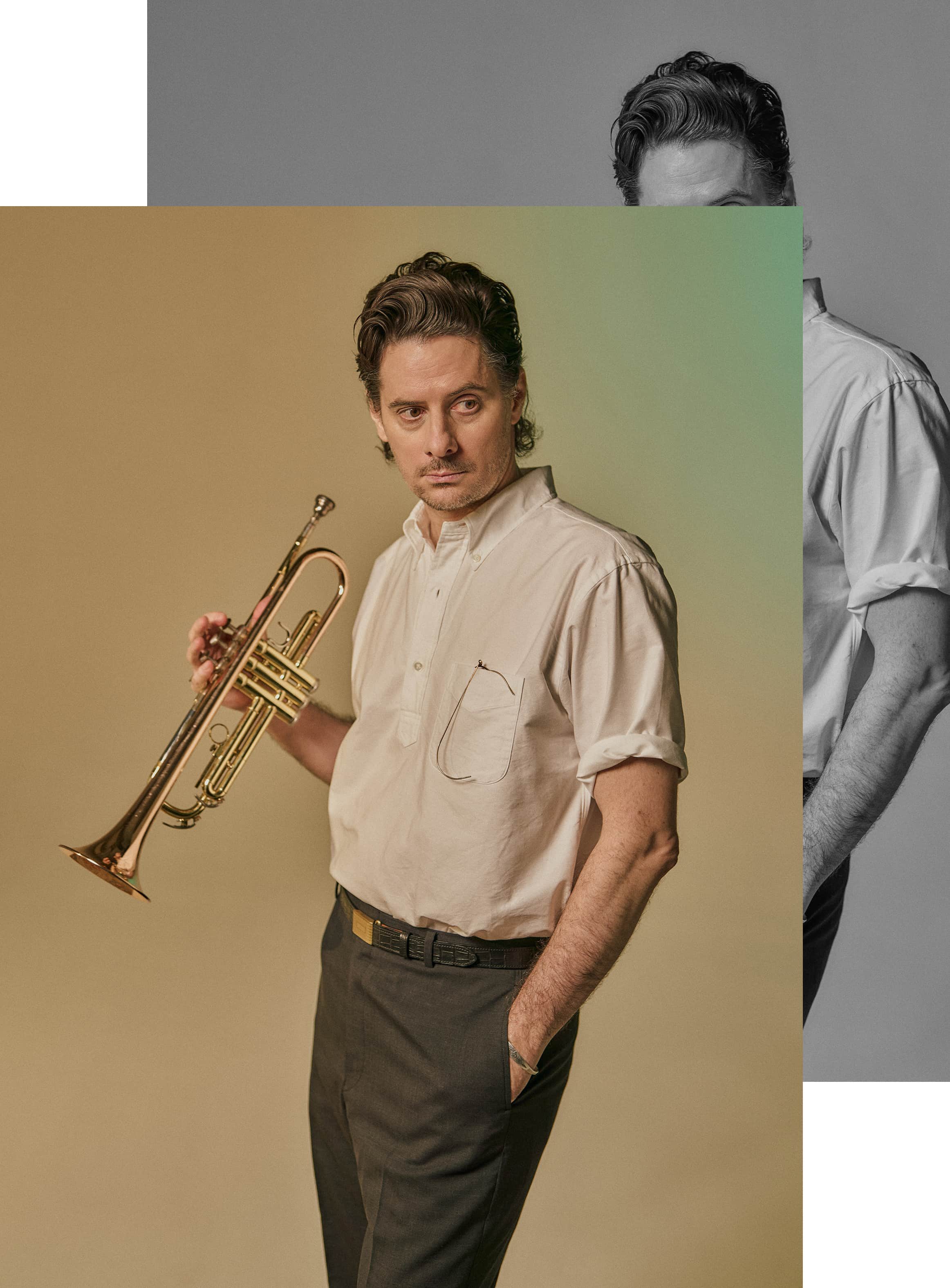 Man holding a trumpet, wearing a shirt and pants, with a neutral expression.