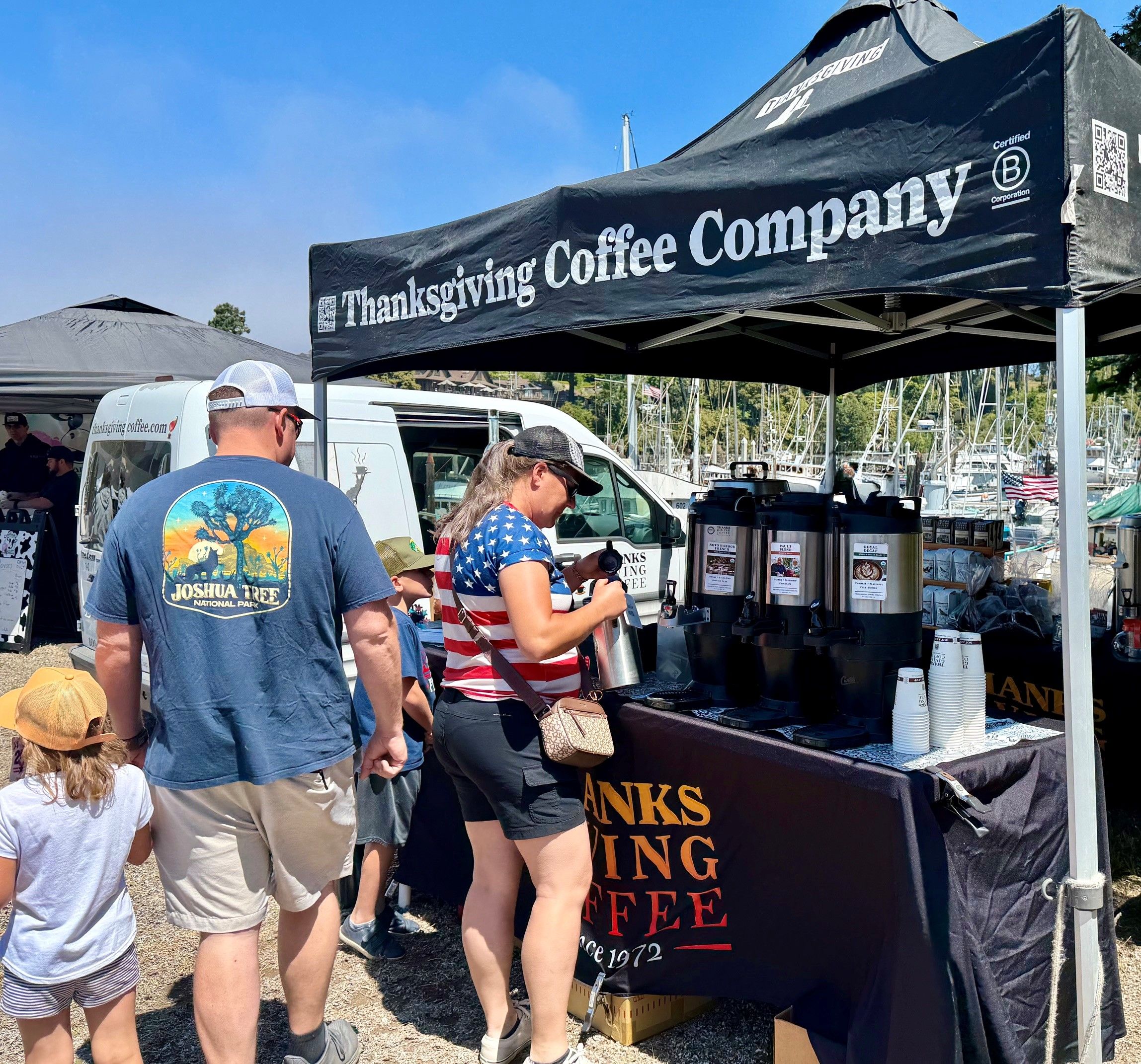 People at our coffee stand under a tent on a sunny day.