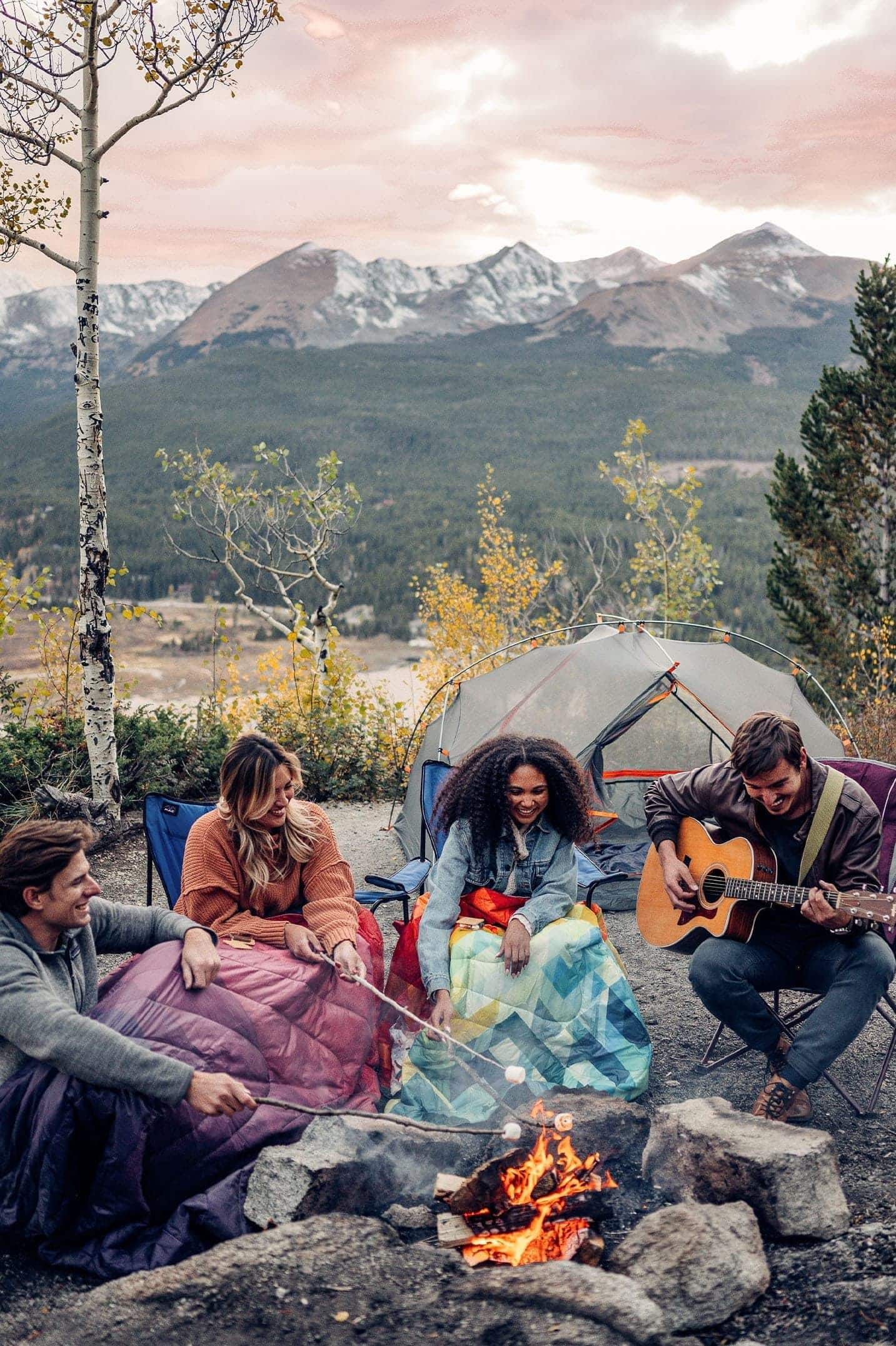 Group of four sitting around a campfire in the mountains with Rumpl blankets