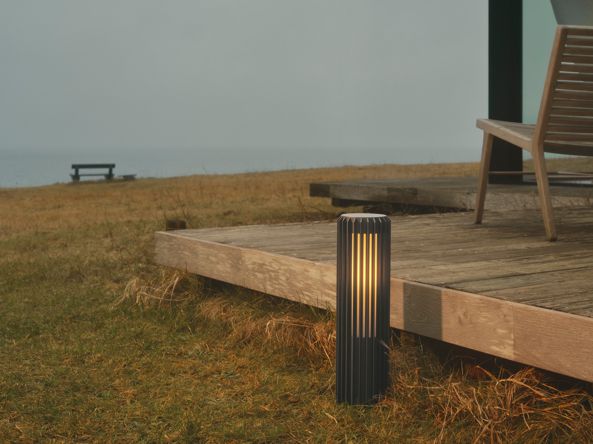 A modern exterior garden light beside a wooden deck