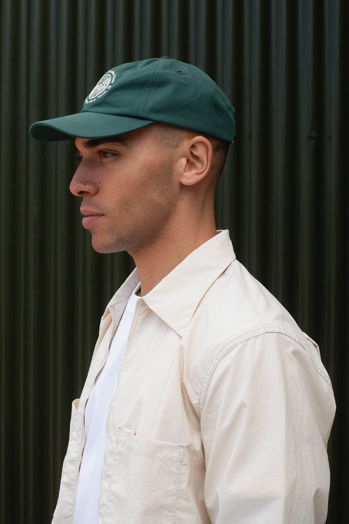 Profile view of a man wearing a green cap and white shirt.