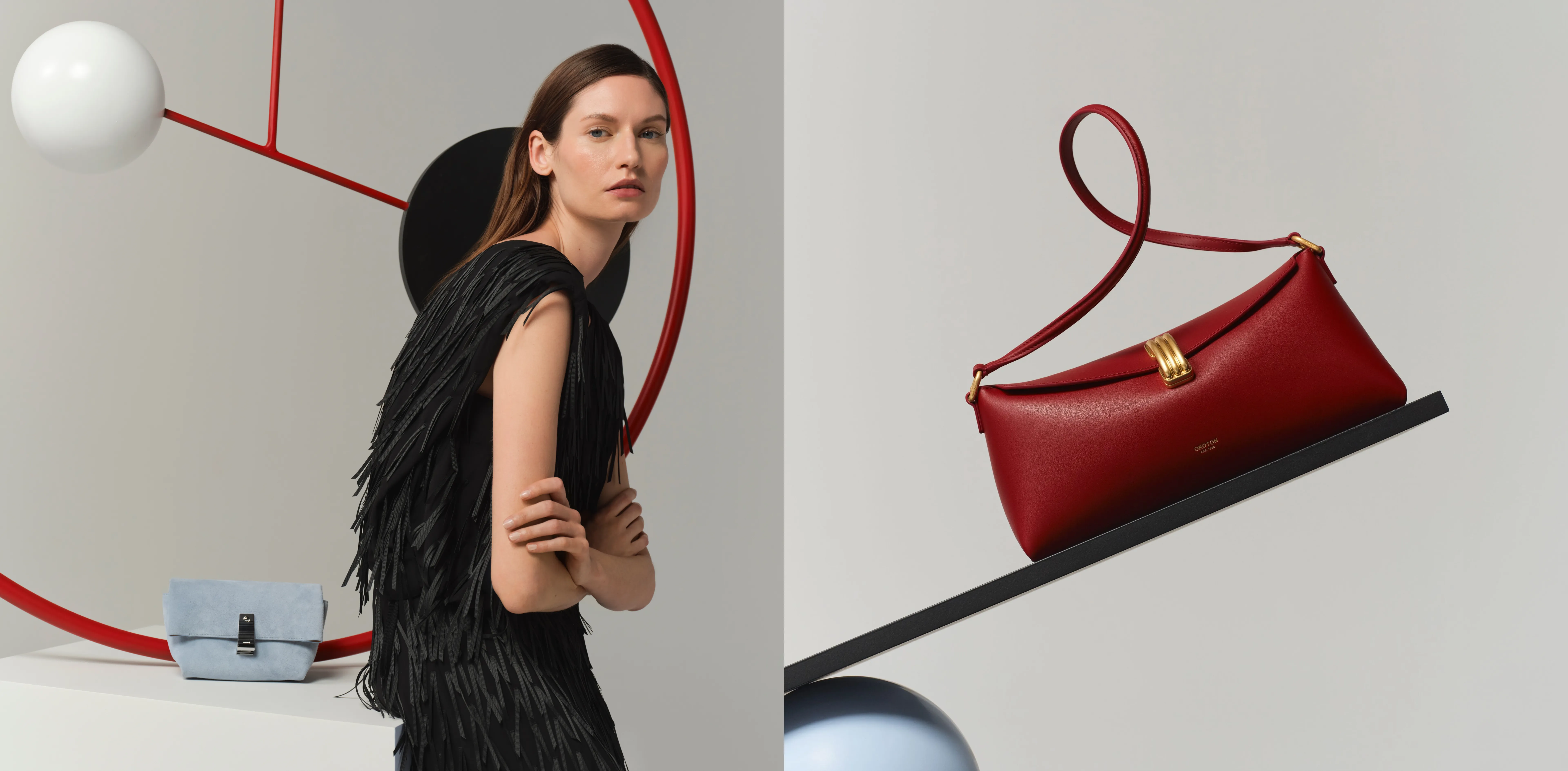 Model posing next to a red handbag and abstract shapes.