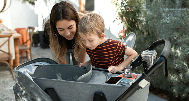 Woman and child looking into a stroller outdoors.