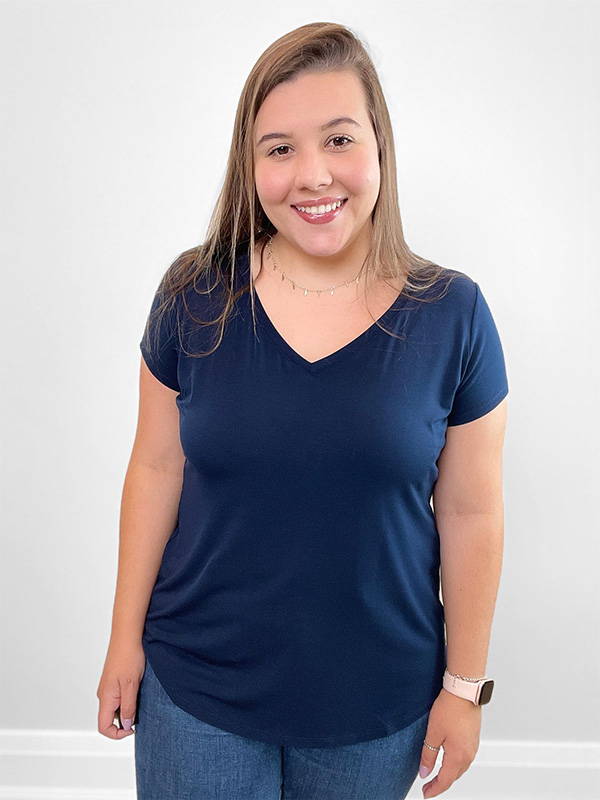 Woman standing in front of a wall wearing Miik's Sutton classic tee in navy with blue jeans.