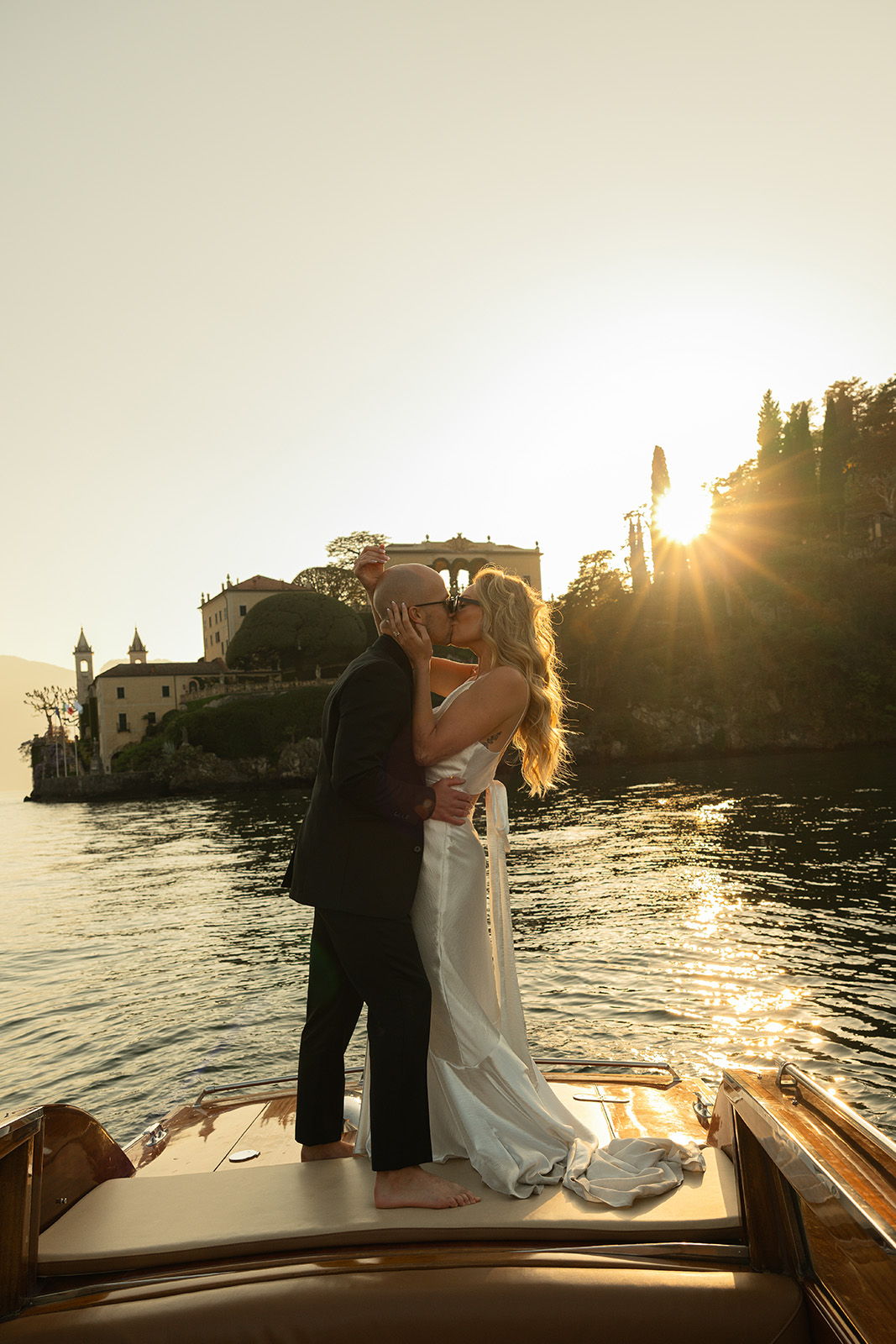 Couple embracing on a boat at sunset by the water.