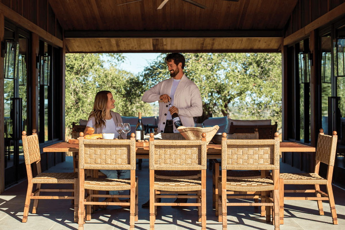 Covered outdoor dining space with woven dining chairs, wood dining table, and natural shade for comfortable outdoor entertaining.