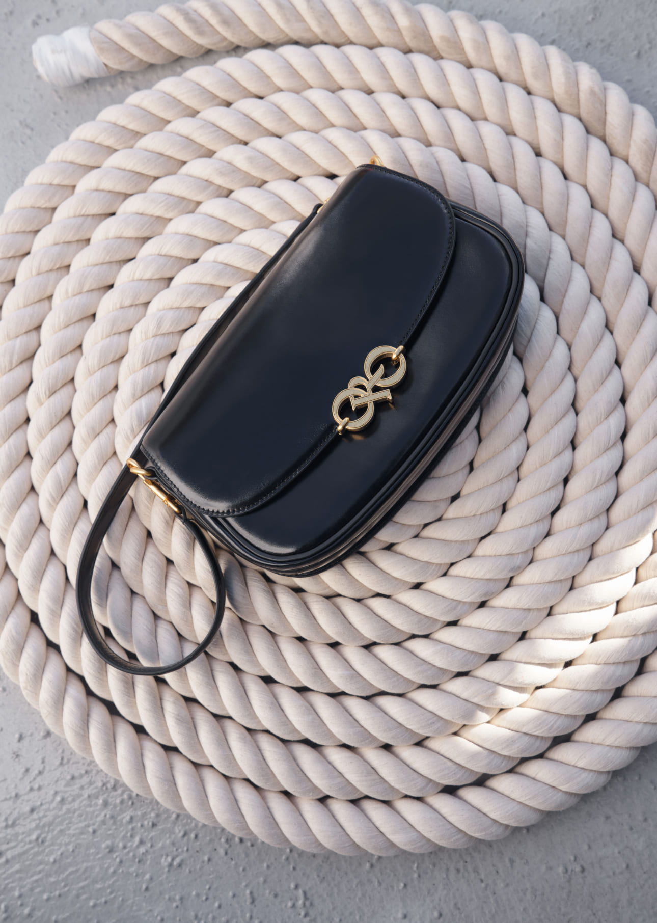 A black handbag resting on a coiled rope background.