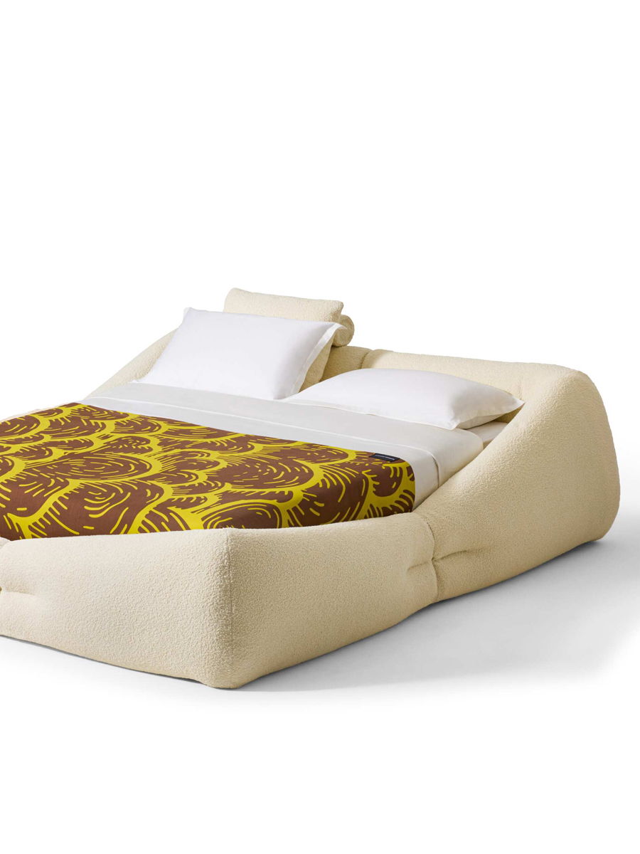 A modern Cassina bed with a unique design and patterned blanket.