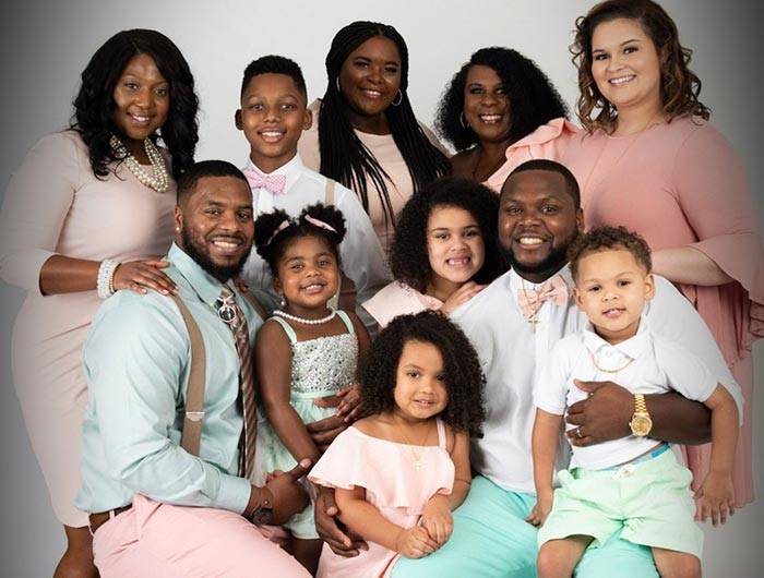 Large family photo with everyone wearing shades of pink and mint